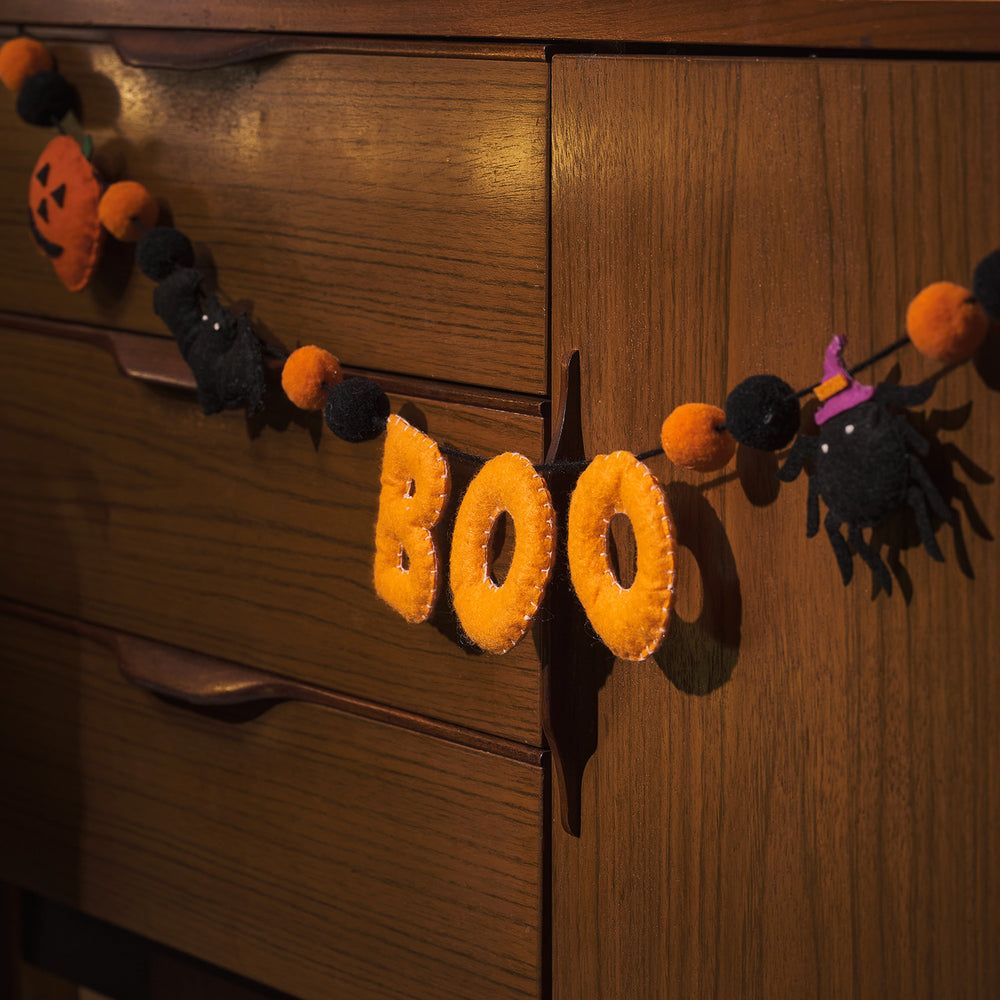Halloween Filzgirlande mit Buchstaben BOO, Kürbis, Fledermaus und Spinne an Holzmöbel
