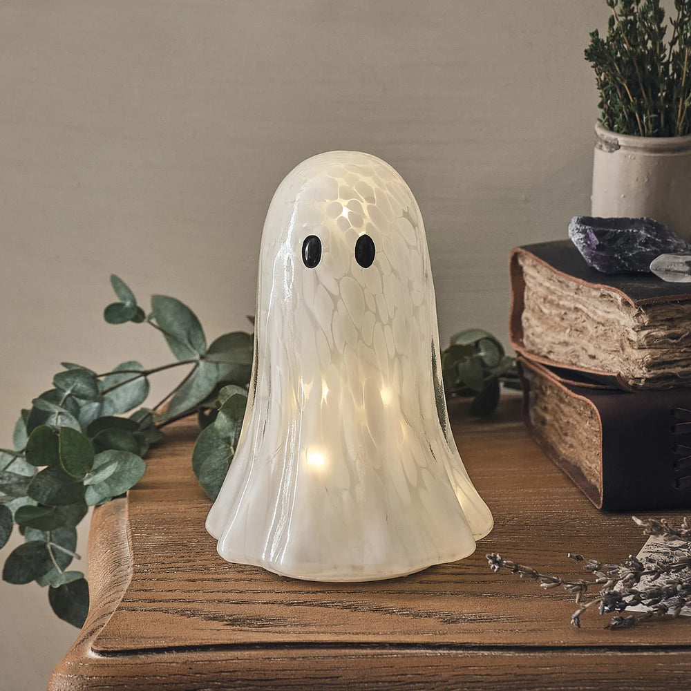 LED-Halloween-Geist aus Konfetti-Glas mit leuchtenden Augen auf Holztisch
