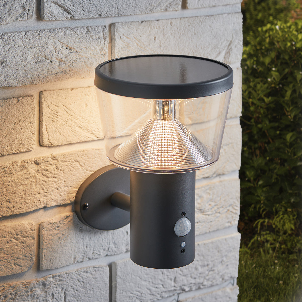 Schwarze LED Solar Wandleuchte mit Bewegungssensor an heller Steinwand montiert