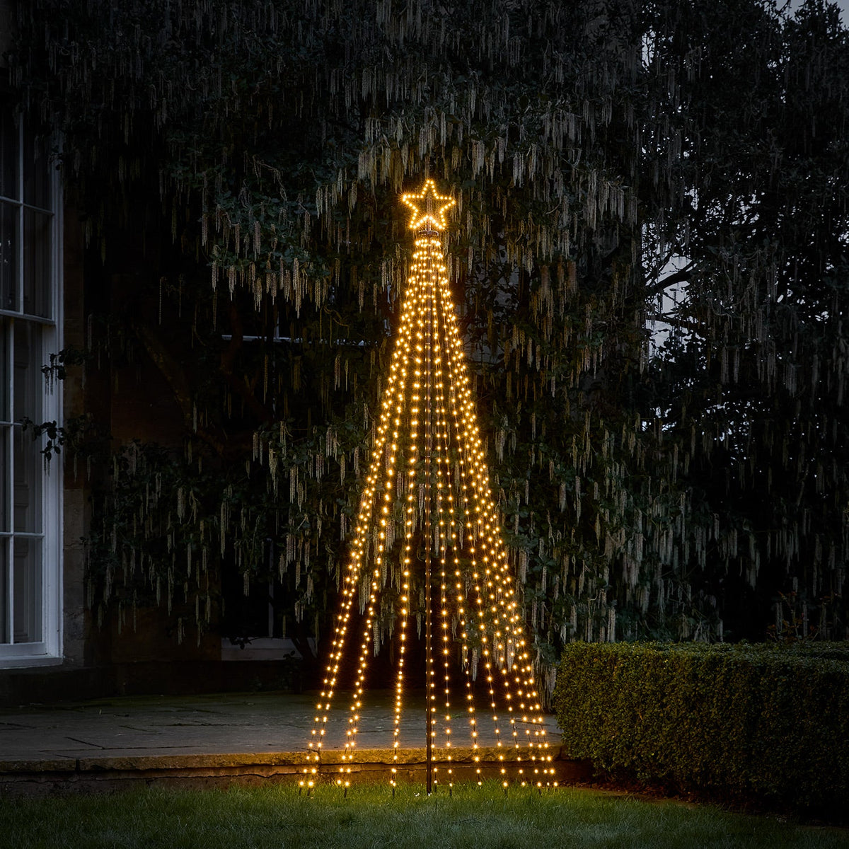 Drei beleuchtete LED-Weihnachtsbäume unterschiedlicher Größe mit Sternen im Garten bei Nacht