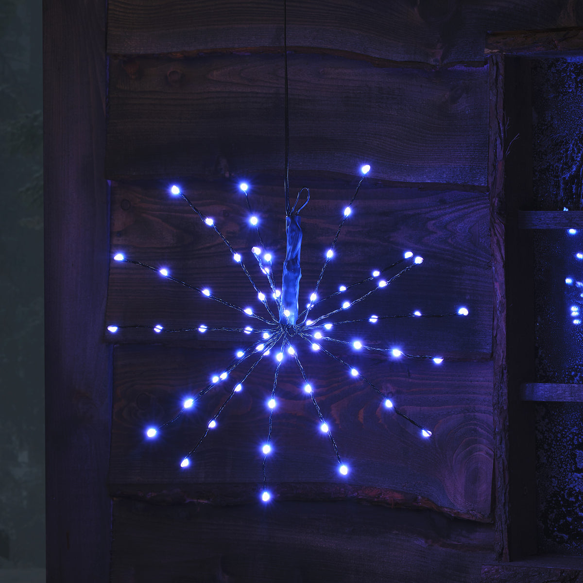 LED Starburst Weihnachtsdeko mit hellblauen LEDs an flexiblen Ästen vor Holz