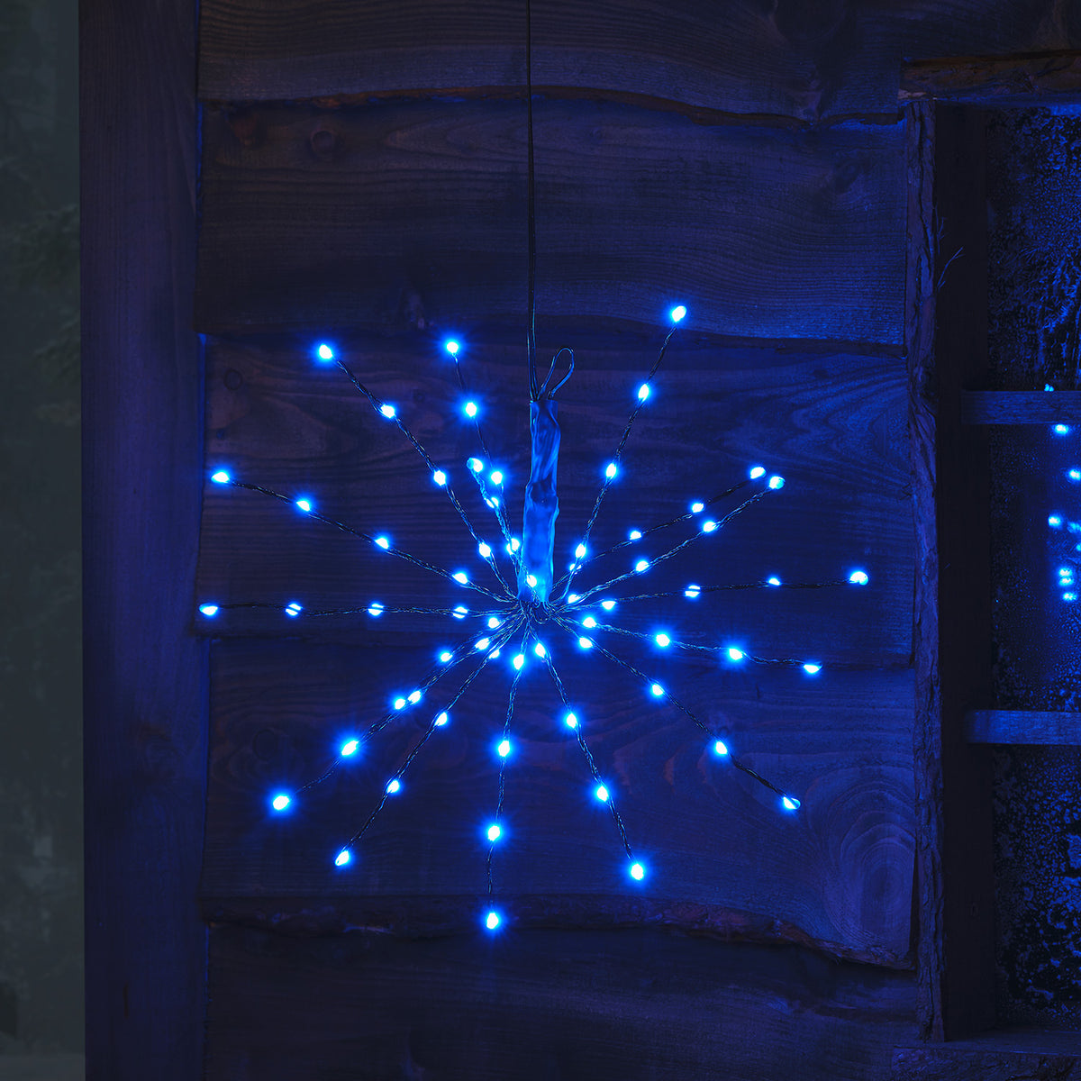 LED Starburst Weihnachtsdeko mit grünen LEDs an flexiblen Ästen vor Holz