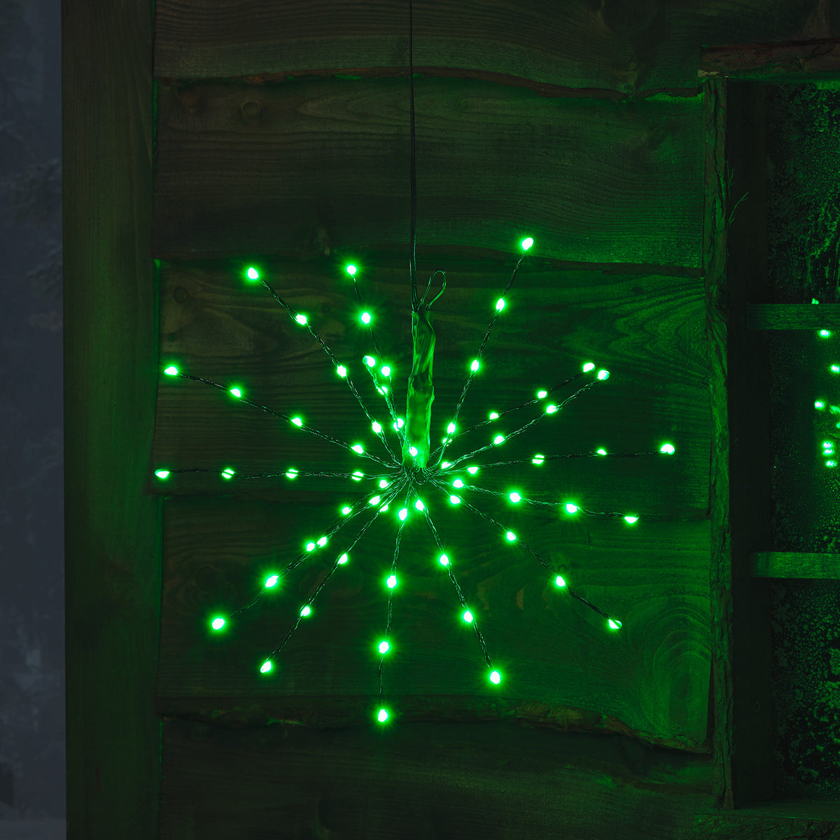 LED Starburst Weihnachtsdeko mit hellgrünen LEDs an flexiblen Ästen vor Holz