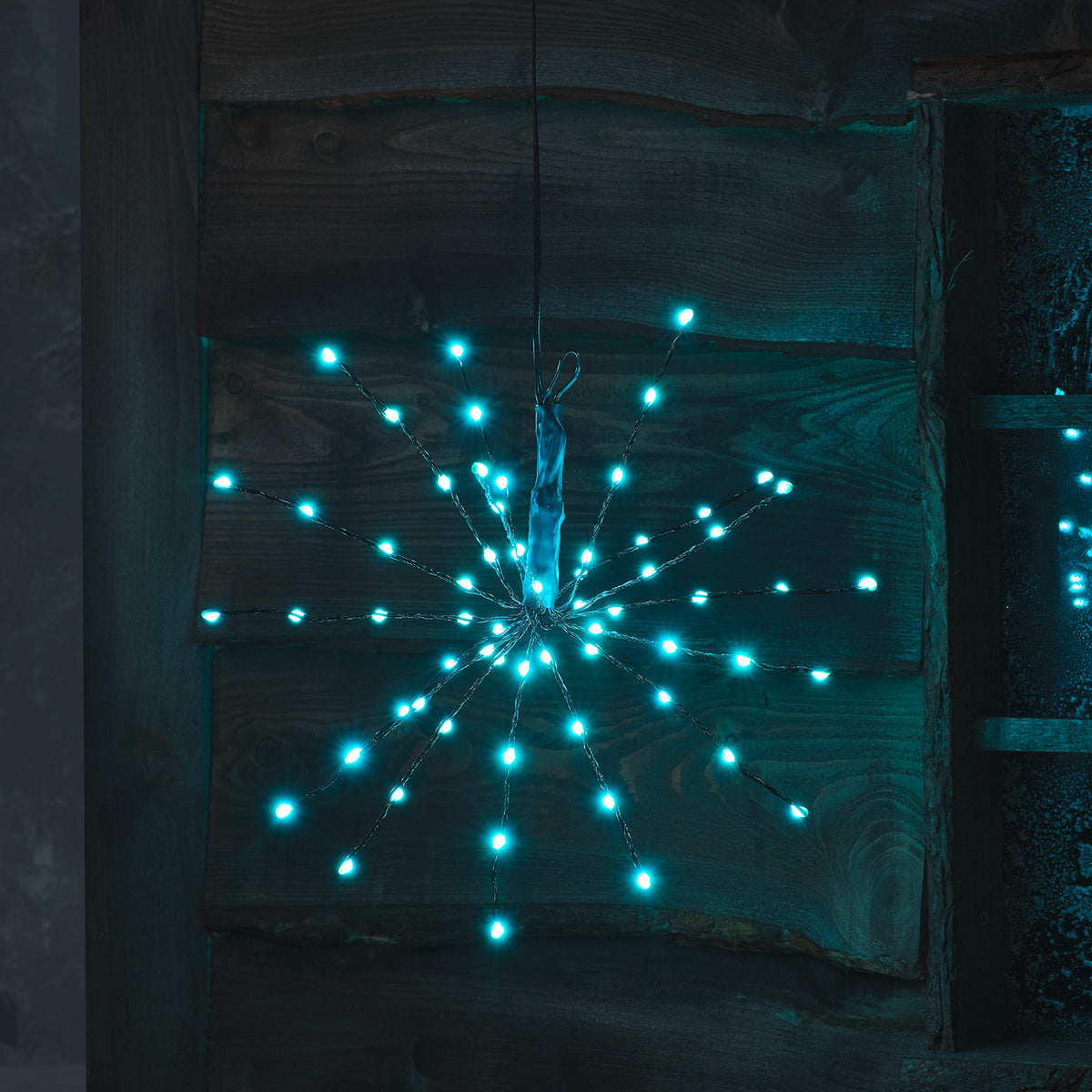 Leuchtender LED Starburst Weihnachtsstern mit blauen Lichtern an Holzwand hängend