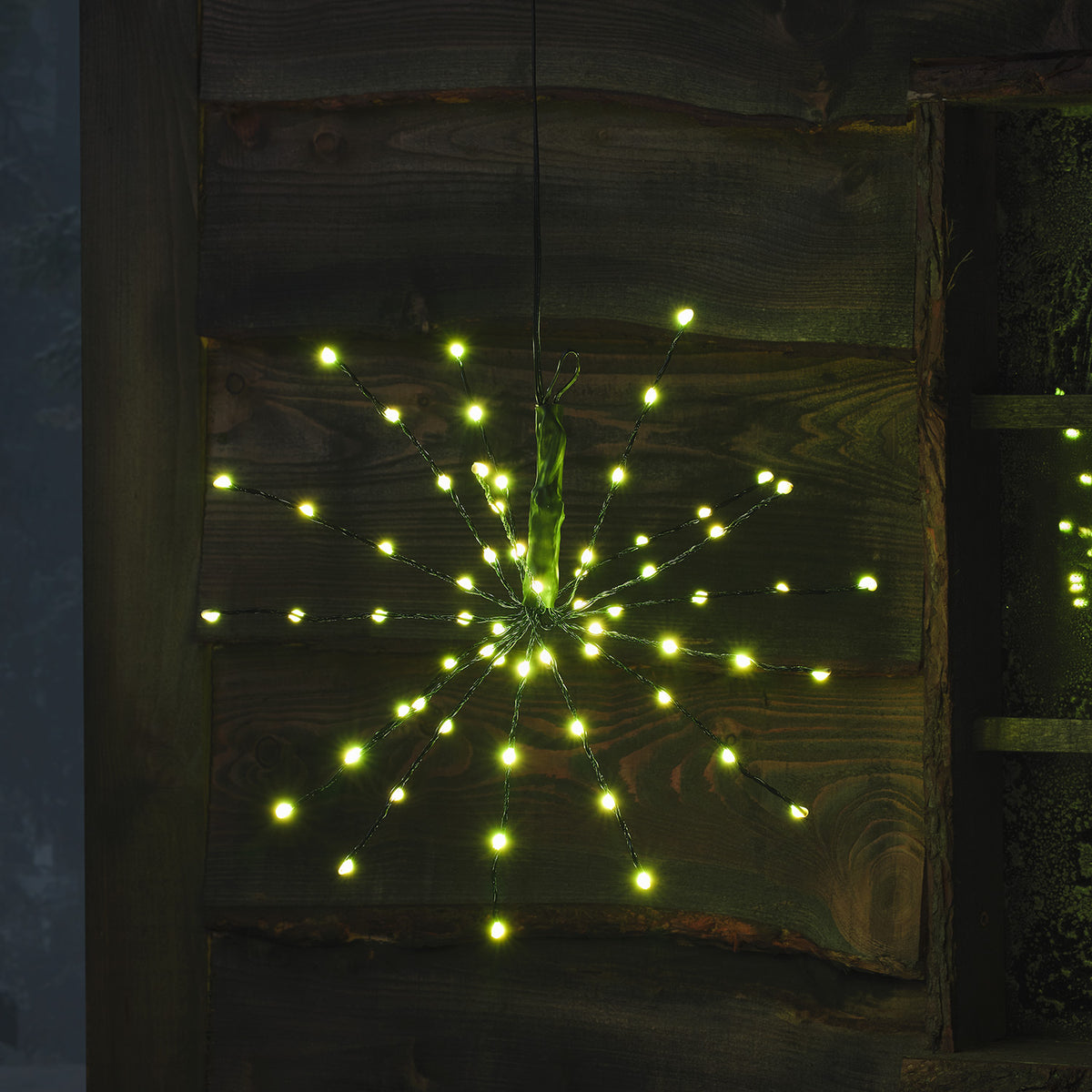 LED Starburst Weihnachtsdeko mit pinkfarbenen LEDs an flexiblen Ästen vor Holz