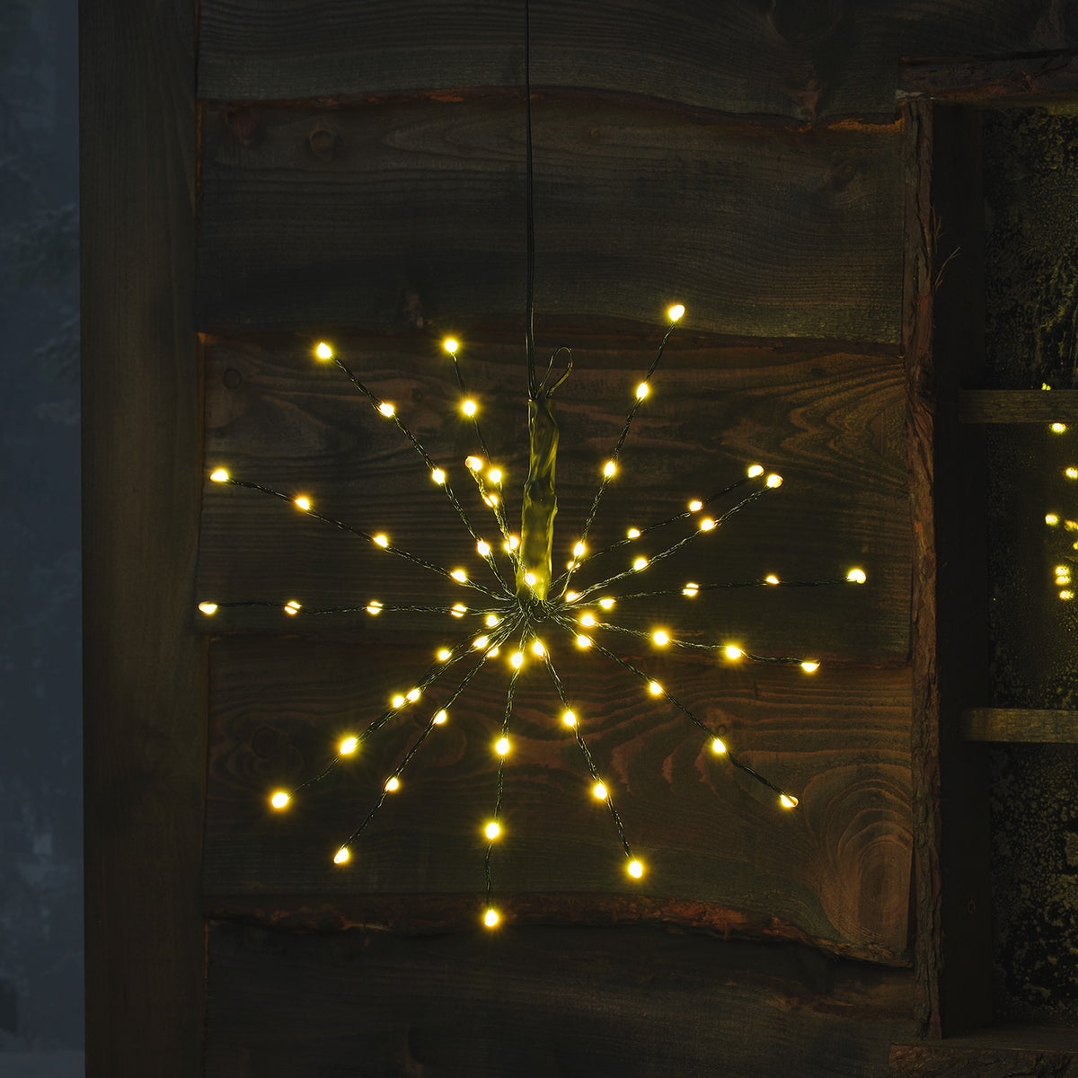 LED Starburst Weihnachtsdeko mit warmweißen LEDs an flexiblen Ästen vor Holz