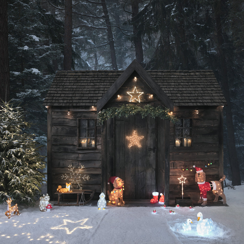 Weihnachtlich dekorierte Holzhütte mit beleuchteten Figuren und LED-Schneeflocke