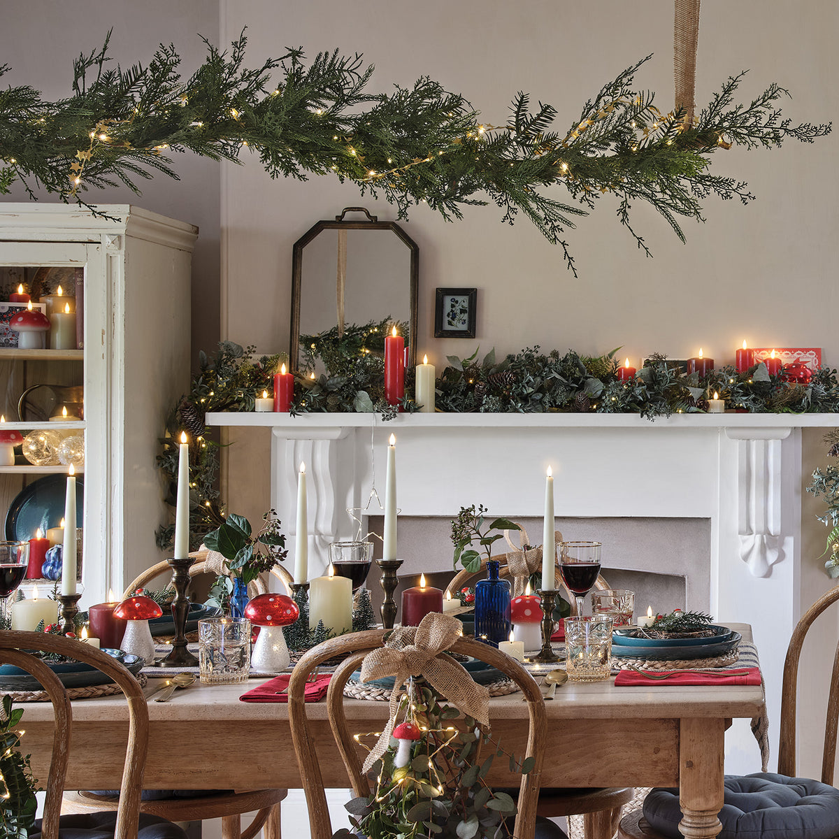 Weihnachtlich dekorierter Essbereich mit Girlande über dem Kamin und Kerzen auf dem Tisch
