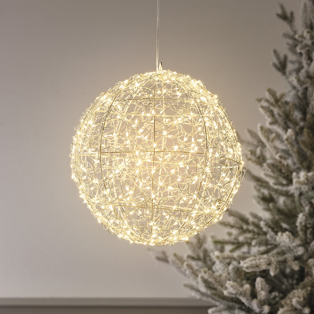 Runde Drahtkugel mit warmweißen Micro-LEDs, aufgehängt vor neutralem Hintergrund