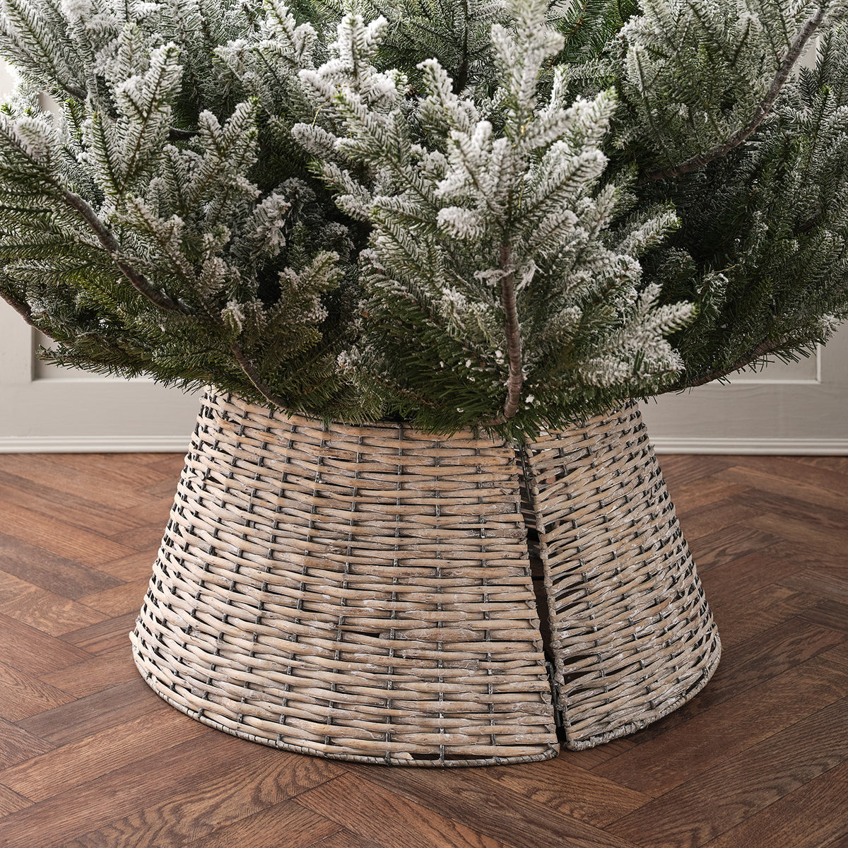 Rattan Weihnachtsbaumrock in drei Teilen um einen Baumstamm mit Schneeimitat