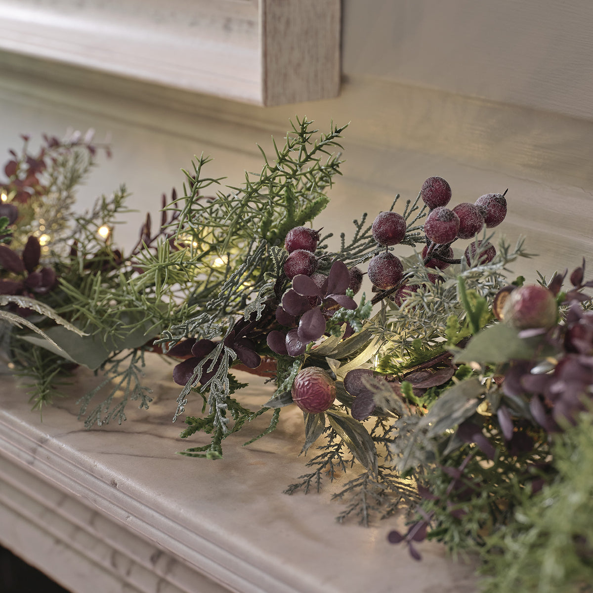 Nahaufnahme der Girlande mit lila Beeren, Tannenzapfen und grünen Kunstzweigen mit LED-Beleuchtung
