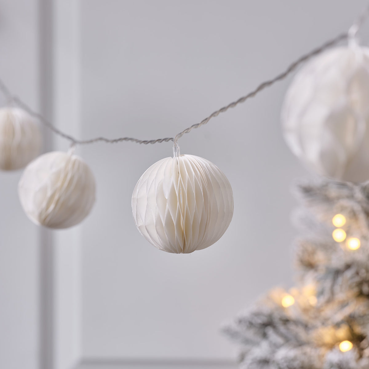 Mehrere cremefarbene Papierkugeln der LED-Lichterkette vor unscharfem Hintergrund