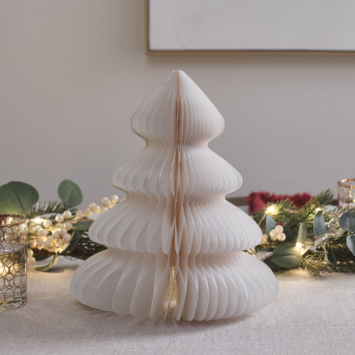 Weißer Papier-Weihnachtsbaum ohne Licht auf Tisch mit Weihnachtsdeko und Kerzen