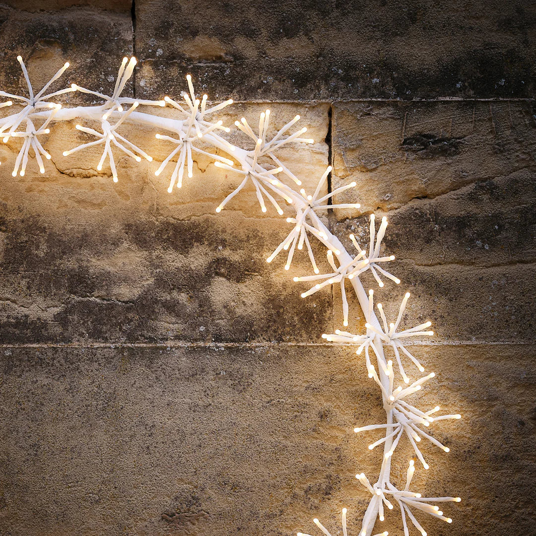 Detailaufnahme der warmweißen LED-Stern-Cluster des Weihnachtskranzes an einer Steinwand