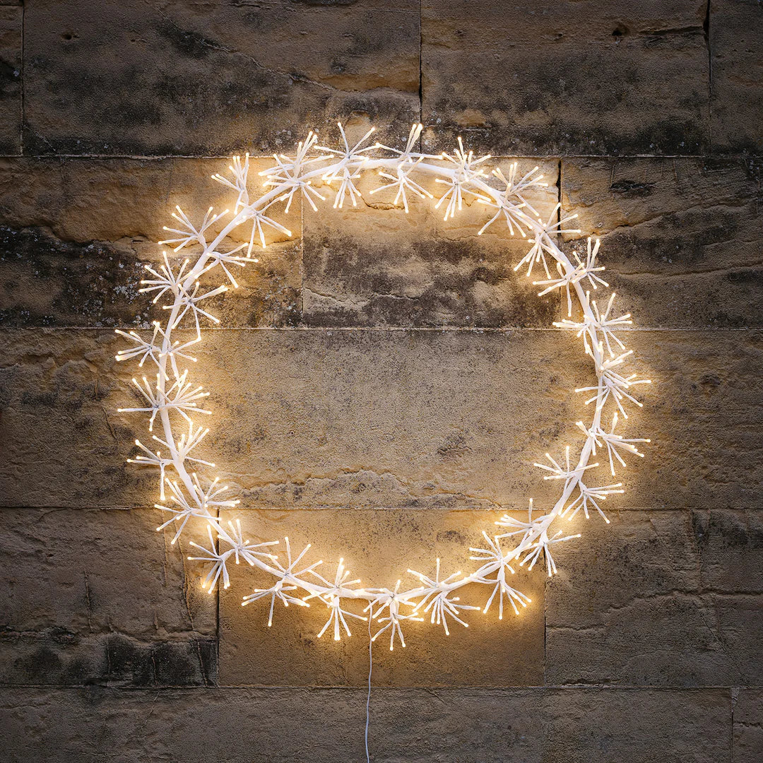 Nahaufnahme des LED Weihnachtskranzes mit sternförmigen Clustern an einer Steinwand