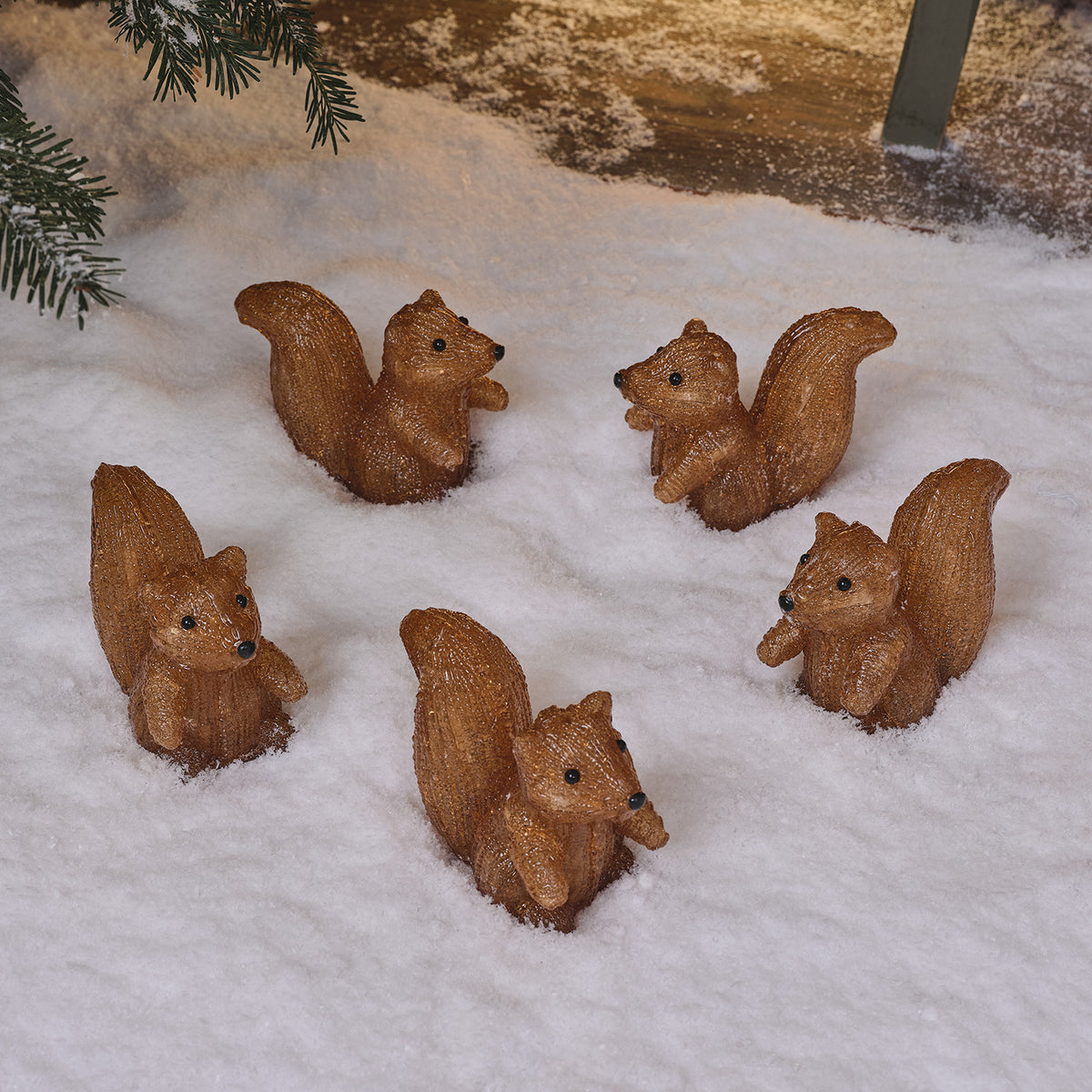 Fünf unbeleuchtete Acryl-Eichhörnchenfiguren im Schnee aufgereiht