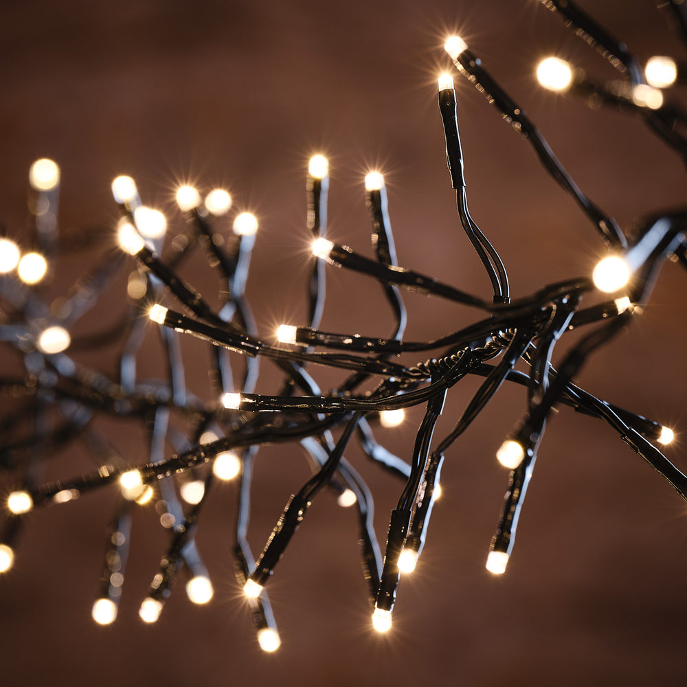 Nahaufnahme warmweißer LED-Lichter auf schwarzem Kabel mit unscharfem braunem Hintergrund