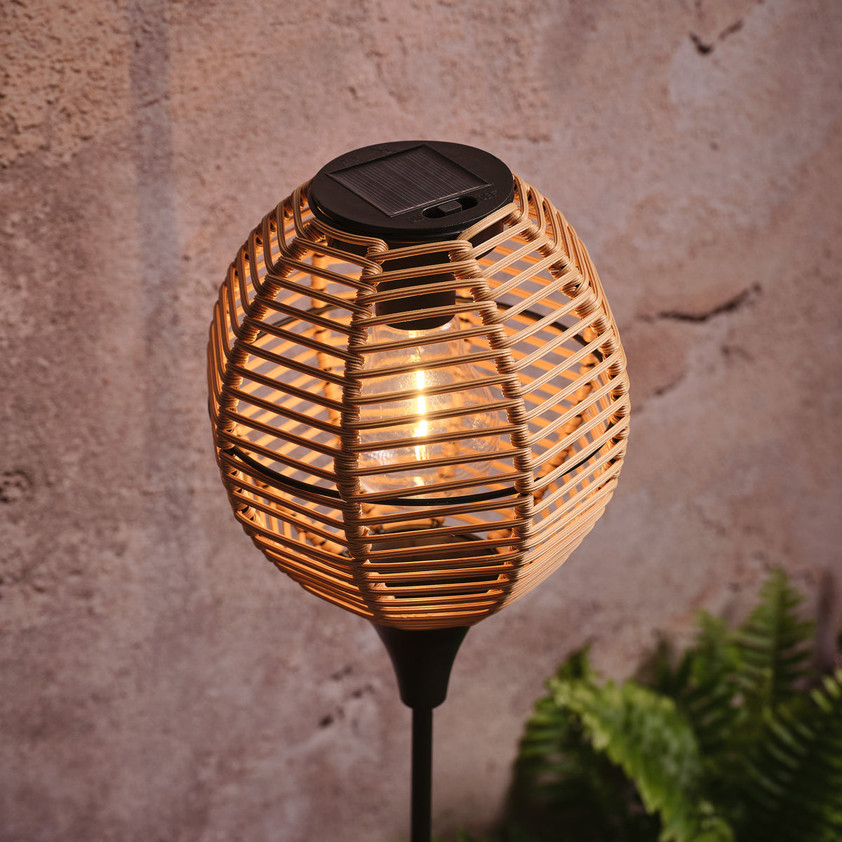 Nahaufnahme Solar-Gartenstecker mit warmweiß leuchtender LED in Rattan-Flechtoptik