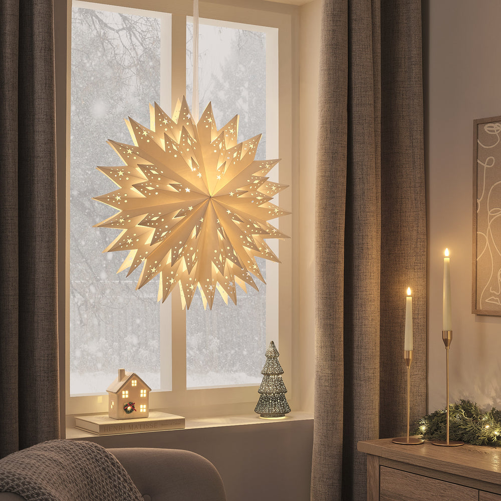 Beleuchteter LED Papierstern mit warmweißem Licht hängt vor Fenster mit winterlicher Schneelandschaft