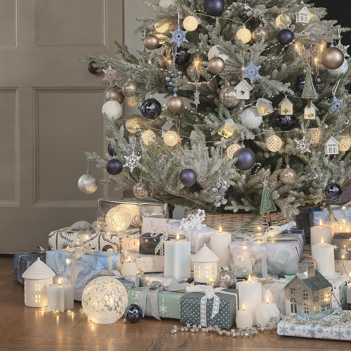 Weihnachtlich geschmückter Baum mit Geschenken im Wohnzimmer.