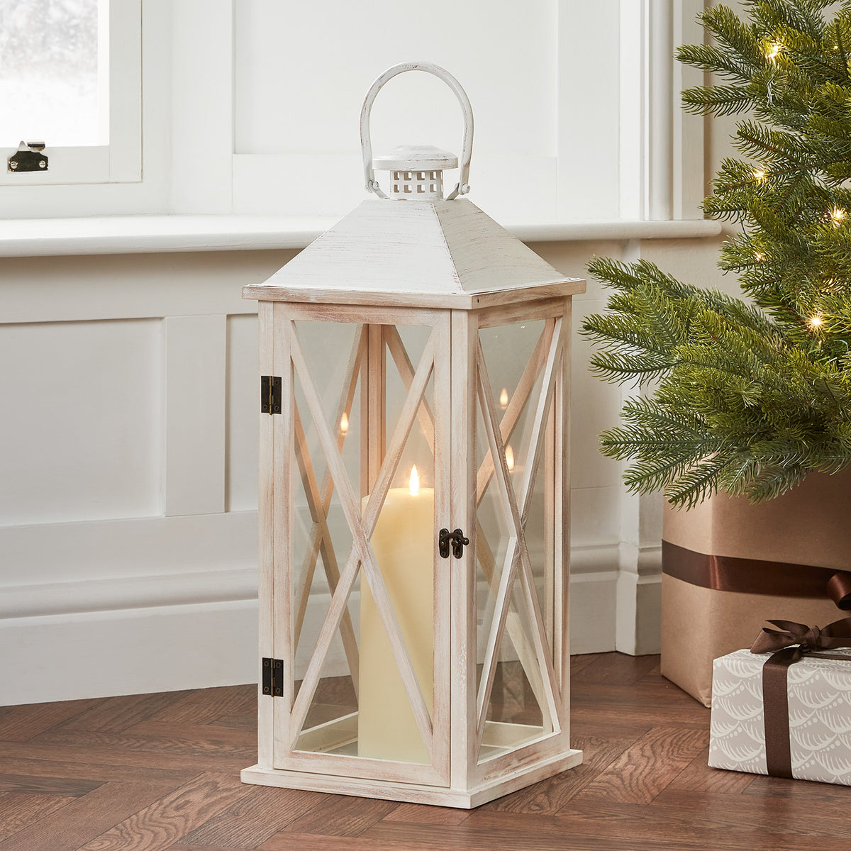 Große weiße Holzlaterne mit TruGlow LED Kerze neben Weihnachtsbaum und Geschenken