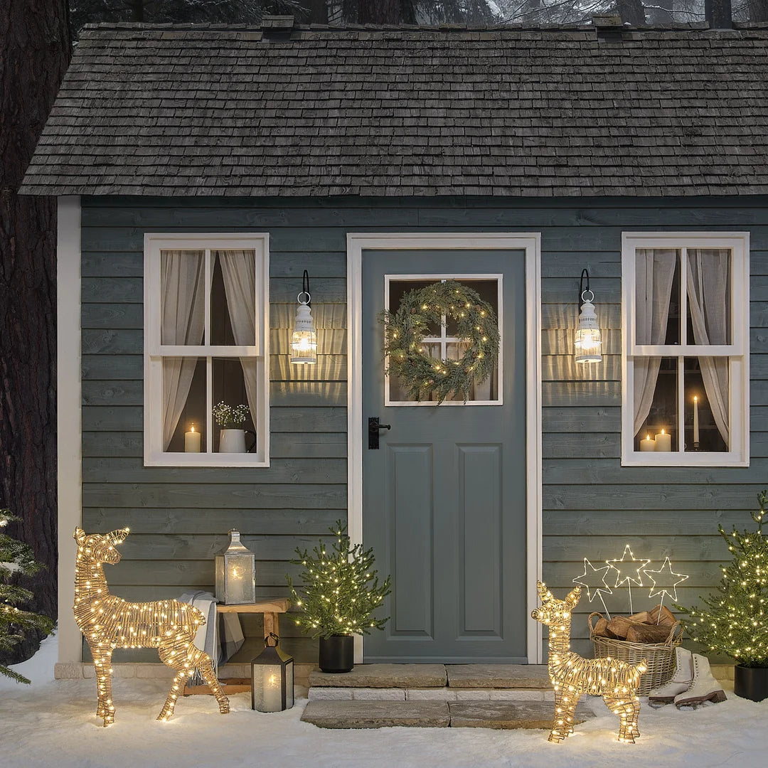 Weihnachtlich dekorierte Hauseingang mit Kranz, Rentierfiguren und blauer Fassade.