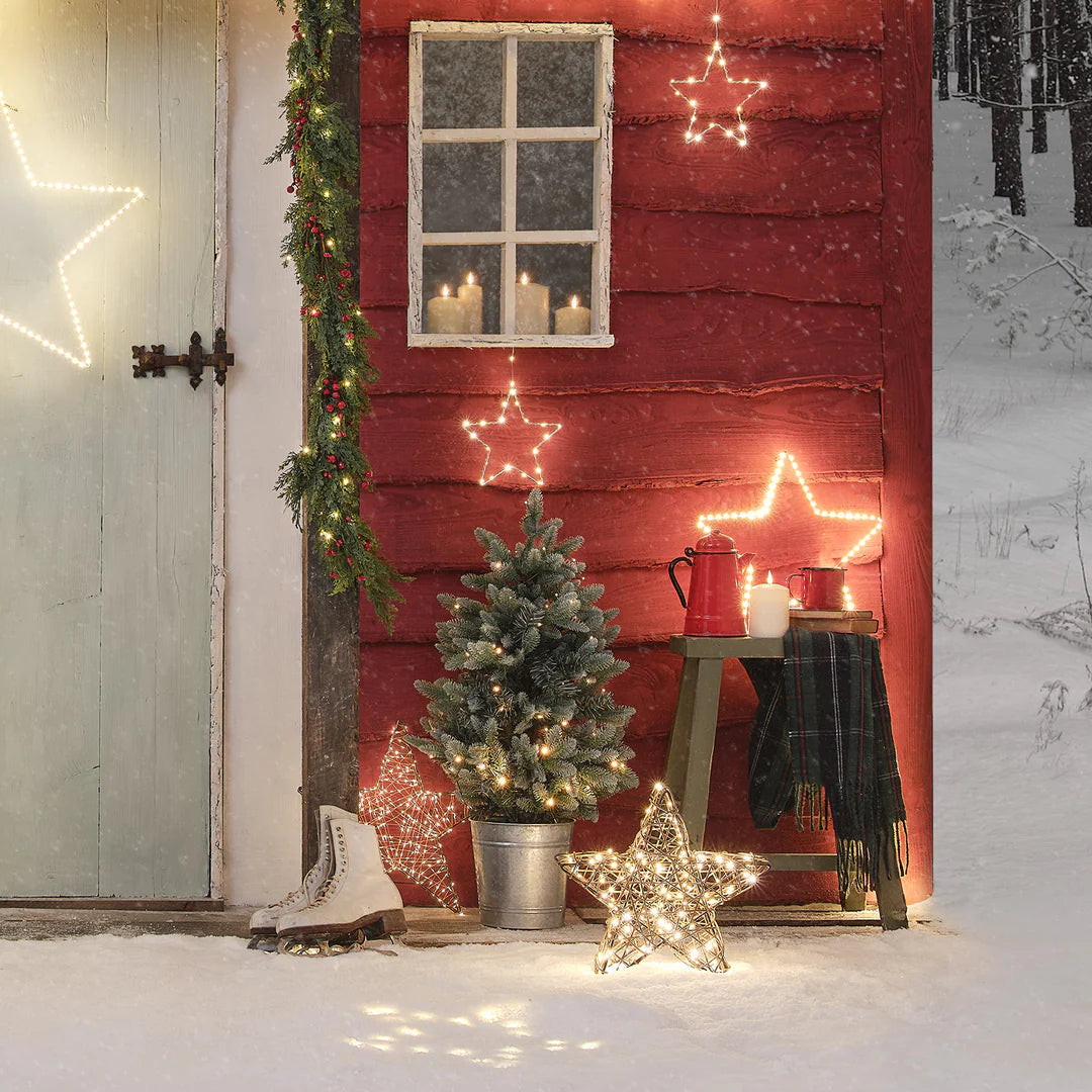 Weihnachtliche Außen-Deko mit Rattan-LED-Stern, Tannenbaum und Schlittschuhen im Schnee