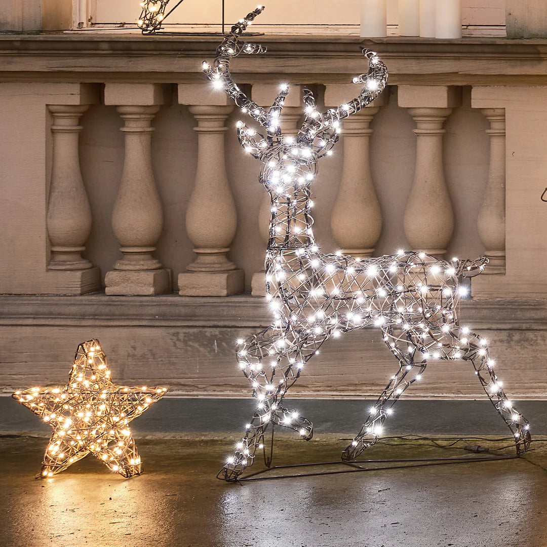Beleuchteter Rattan-Stern neben beleuchtetem LED-Reh vor Steinbalustrade
