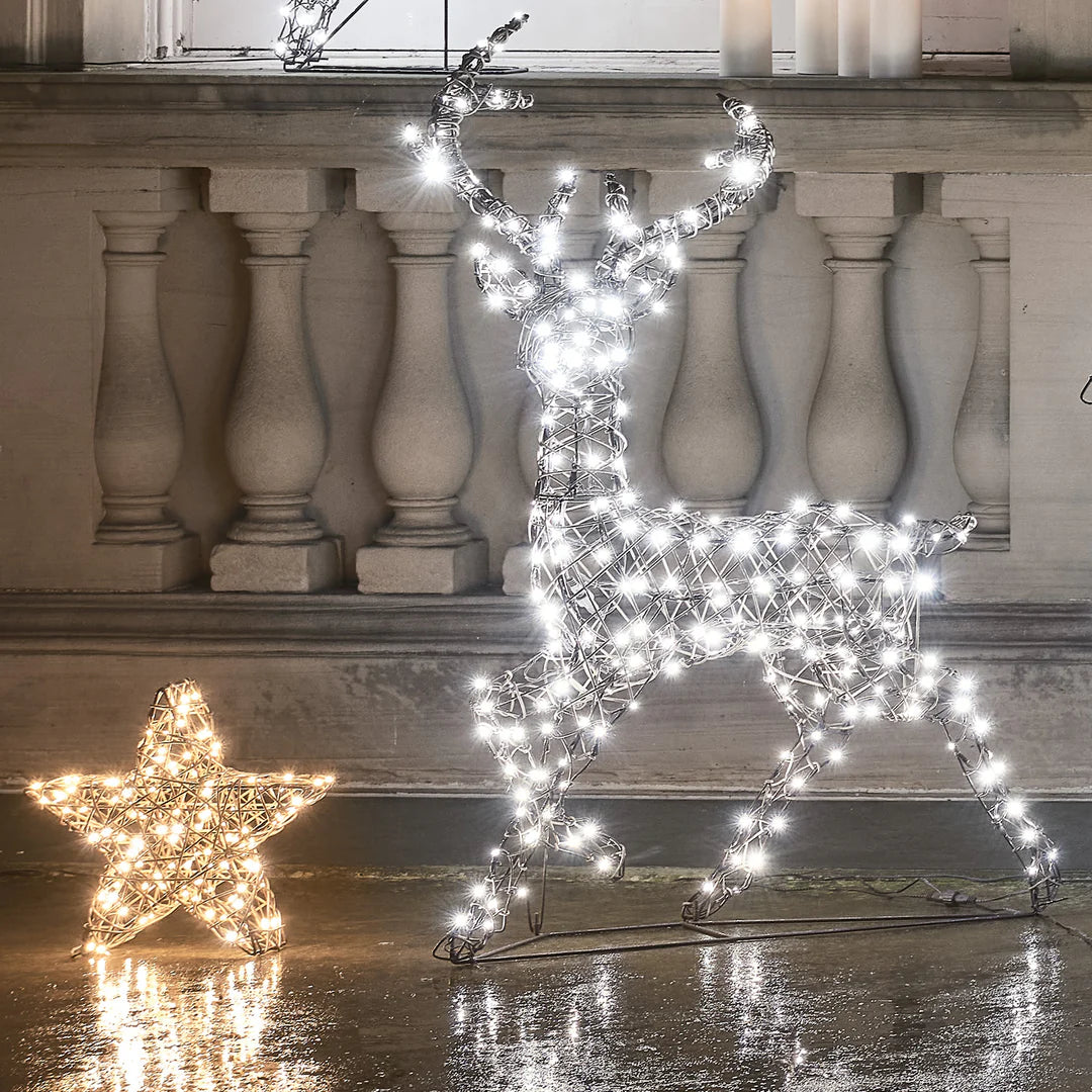 LED-Rentier mit kaltweißen Lichtern neben beleuchtetem Stern vor Haus
