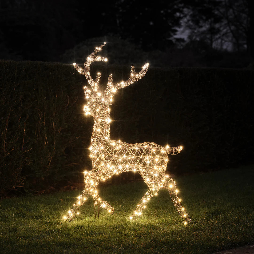 LED-Rentier mit kaltweißen Lichtern im dunklen Garten auf Gras