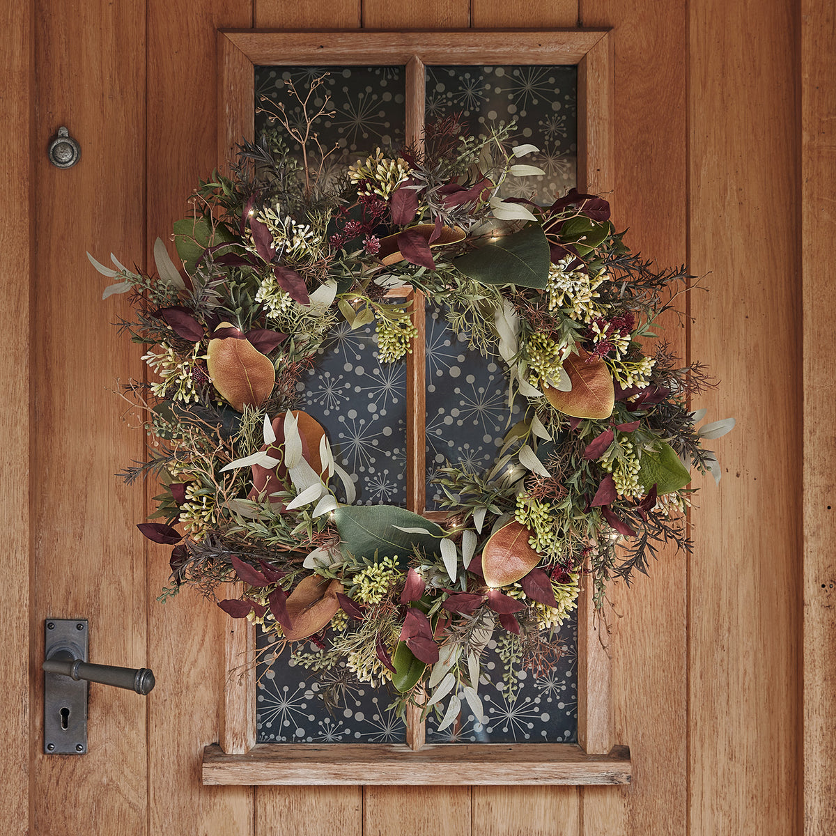 Herbstlicher Türkranz mit roten und grünen Blättern an Holztür