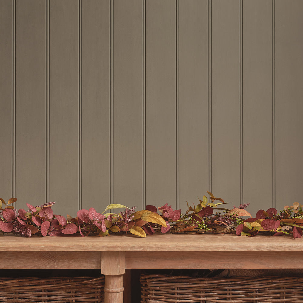 Herbstgirlande mit warmweißen LEDs und buntem Laub in Burgunder und Gelb auf Holztisch