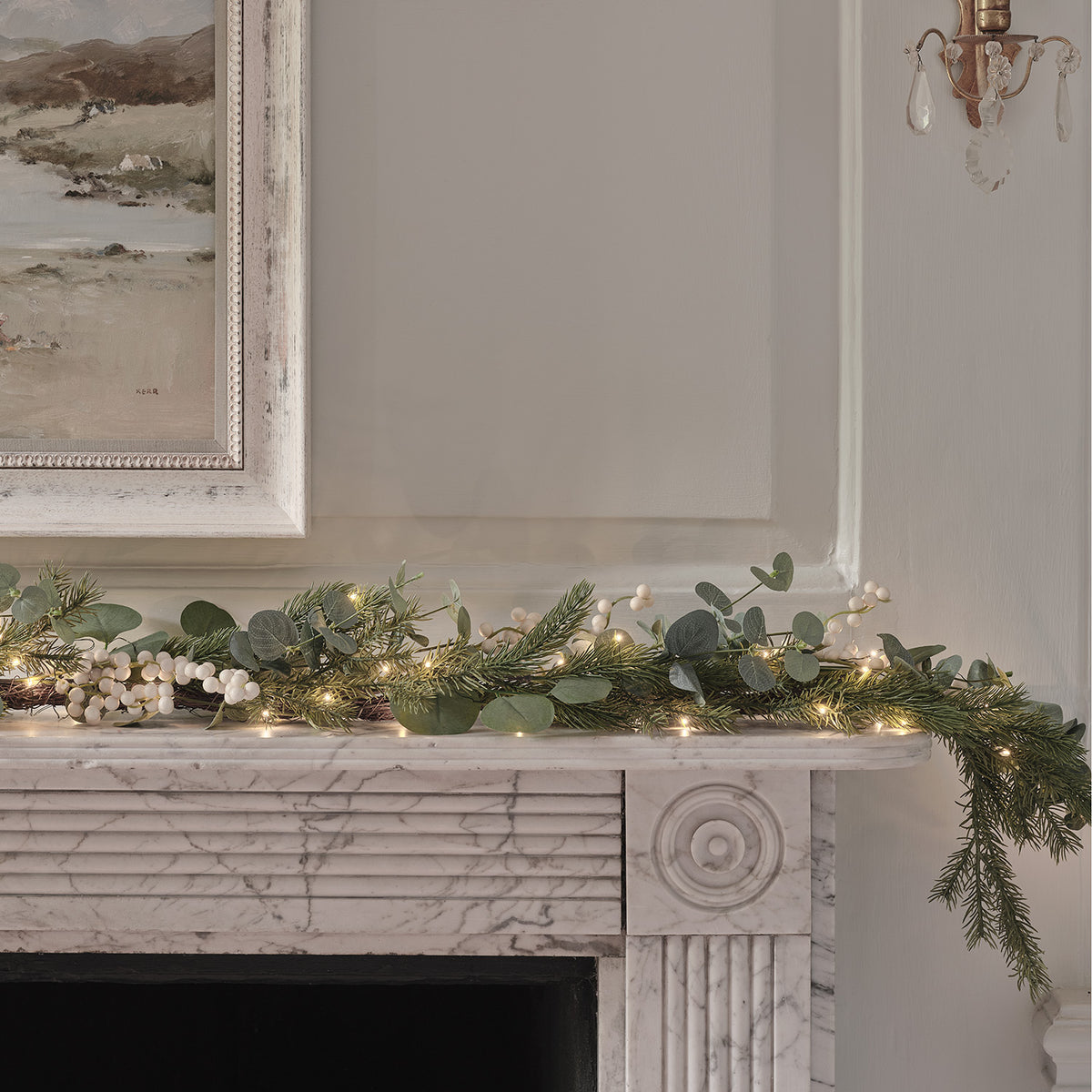 Weihnachtsgirlande mit Eukalyptus und weißen Beeren auf Kaminsims mit warmweißen LEDs