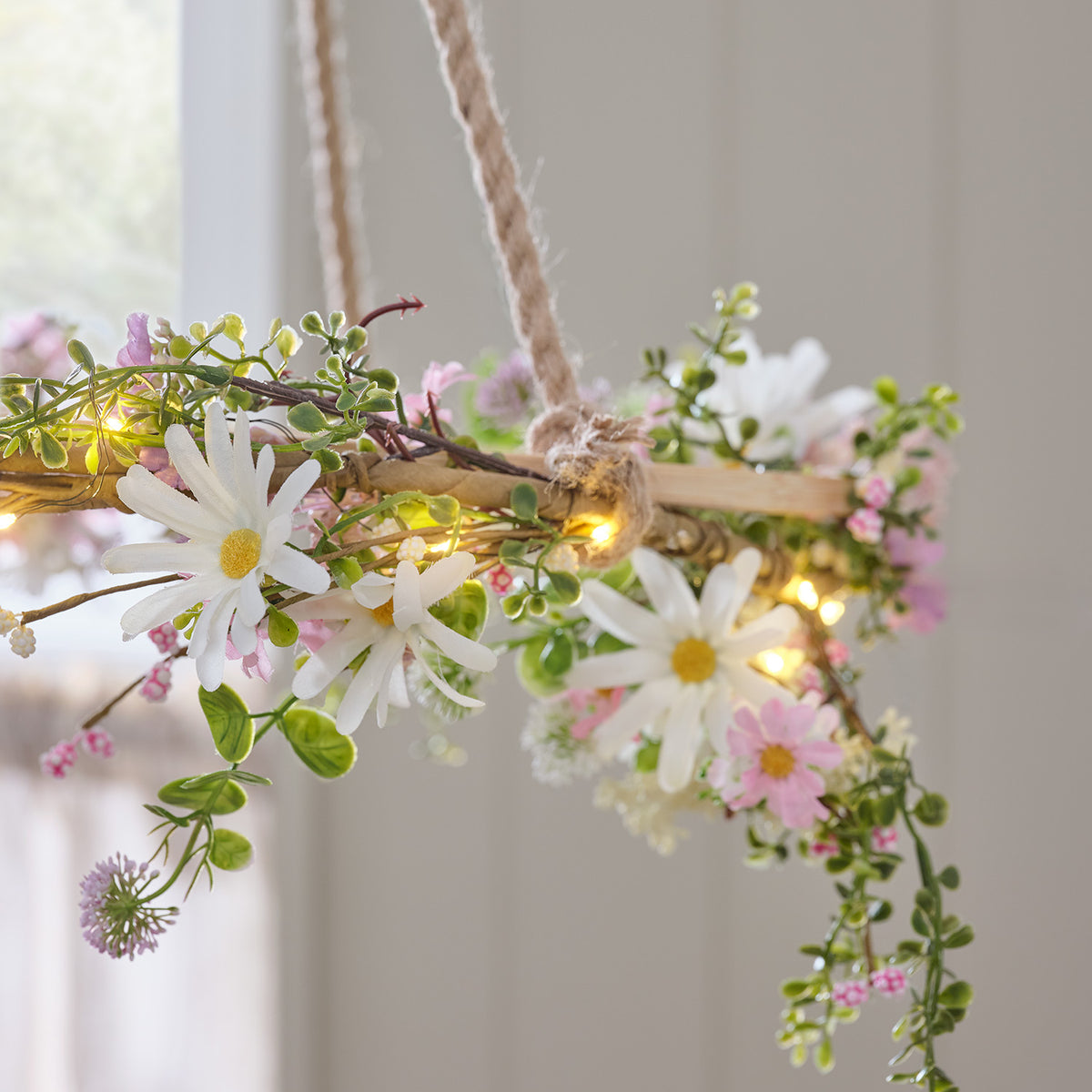 LED-Blumenkranz mit Margeriten und warmweißen LEDs auf Tisch mit Kerzen und Geschirr