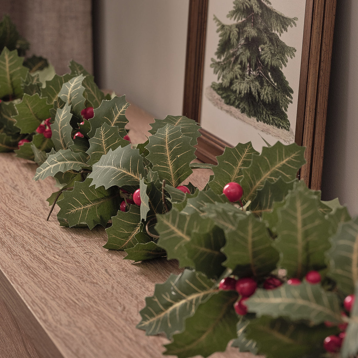 Detailaufnahme der künstlichen Stechpalmenblätter und roten Beeren mit warmweißen LED-Lichtern