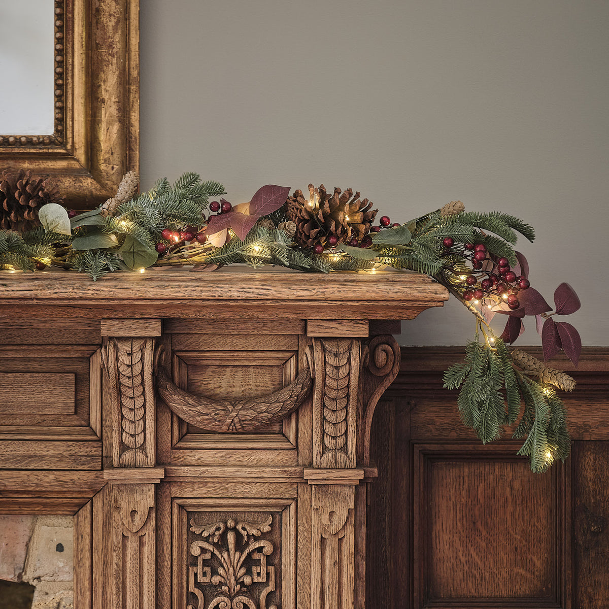 Weihnachtsgirlande mit warmweißen LEDs auf einem antiken Holzsideboard dekoriert