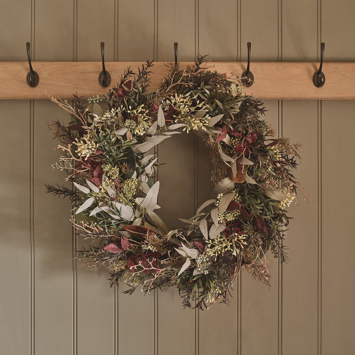 Herbstkranz mit warmweißen LEDs und roten Beeren an Garderobe mit Haken