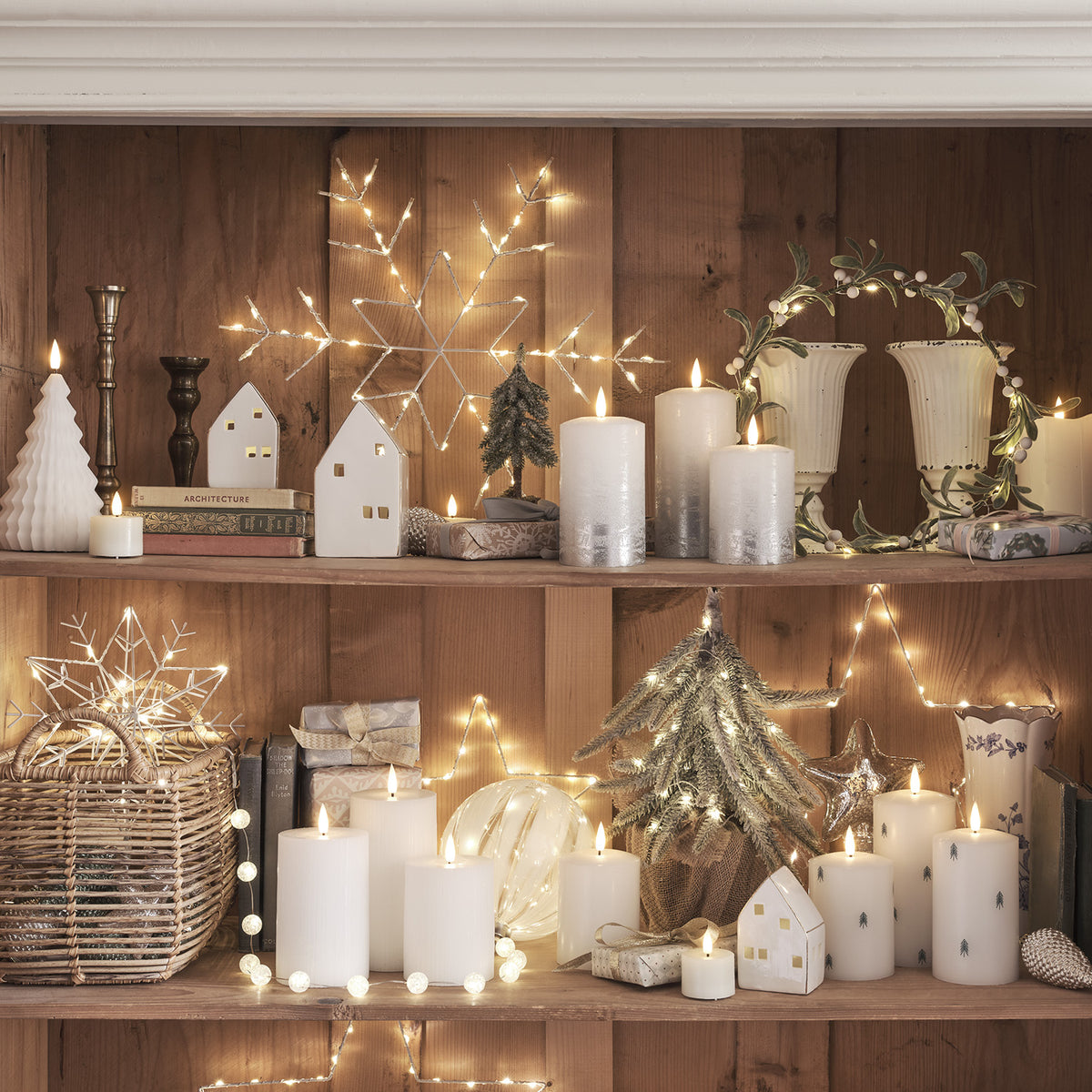 Weihnachtliches Regal mit LED-Mistelzweig-Kranz, Kerzen, Deko-Häusern und beleuchteten Sternen