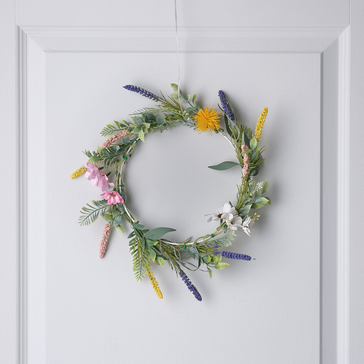 Frühlingskranz mit Lavendel, rosa und weißen Blüten ohne Beleuchtung an weißer Tür