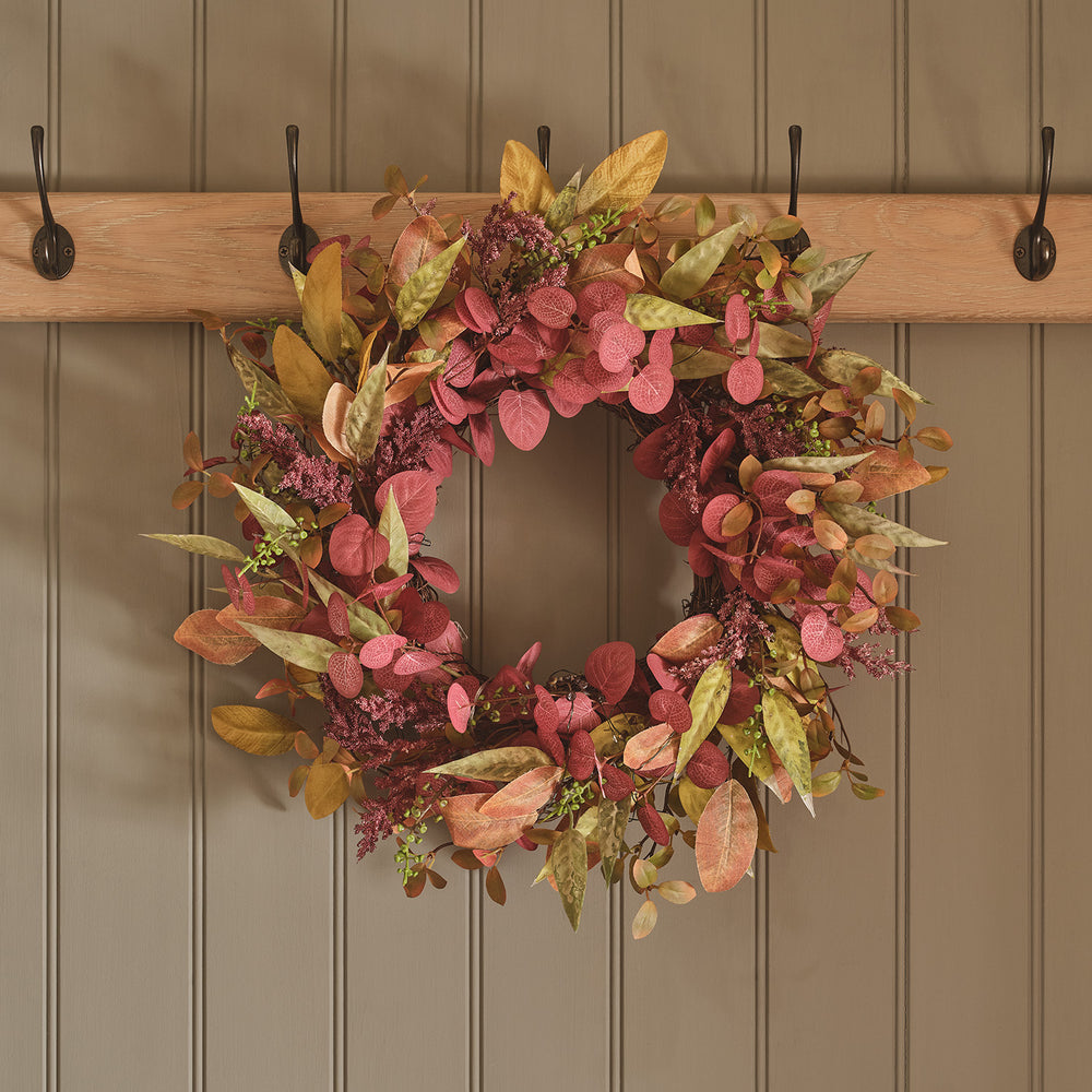 Herbstkranz mit roten und gelben Kunstblättern ohne Beleuchtung an Holzwand