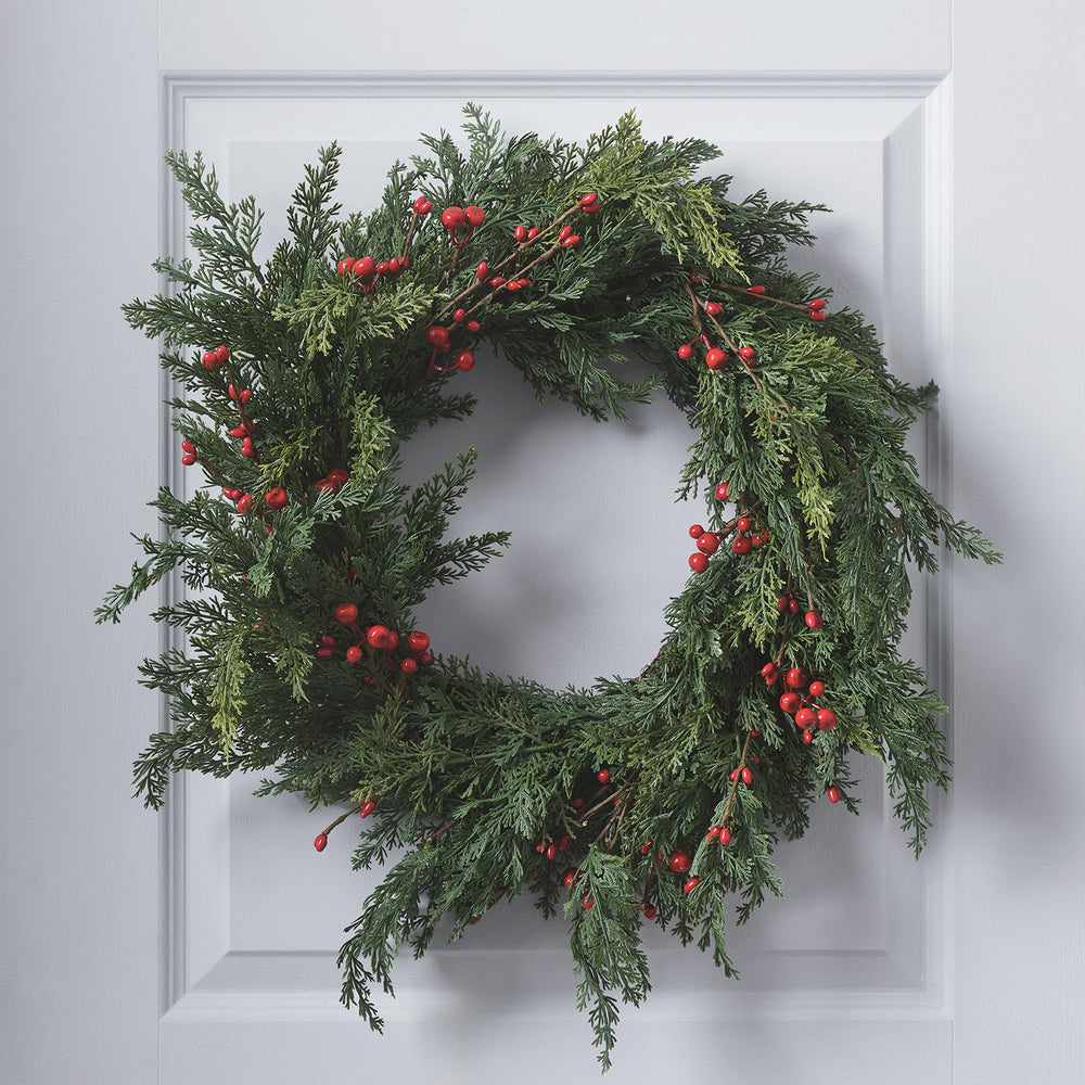Weihnachtskranz mit roten Beeren ohne Beleuchtung an weißer Tür