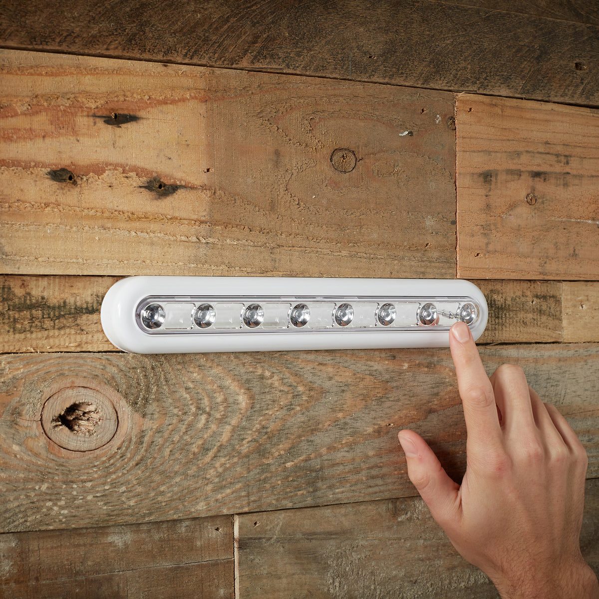 Hand berührt LED Touch Leuchtleiste zum Ein- und Ausschalten an Holzwand