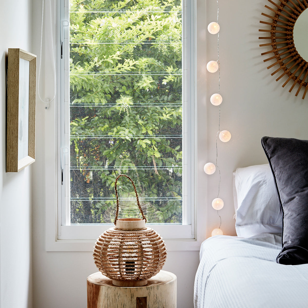 Lichterkette mit Baumwollkugeln hängt neben Fenster mit grünem Blick und Holzdeko