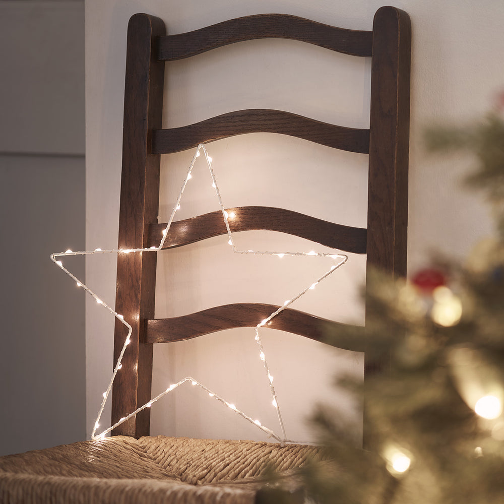 LED Stern mit warmen Micro-Lichtern auf einem dunklen Holzstuhl