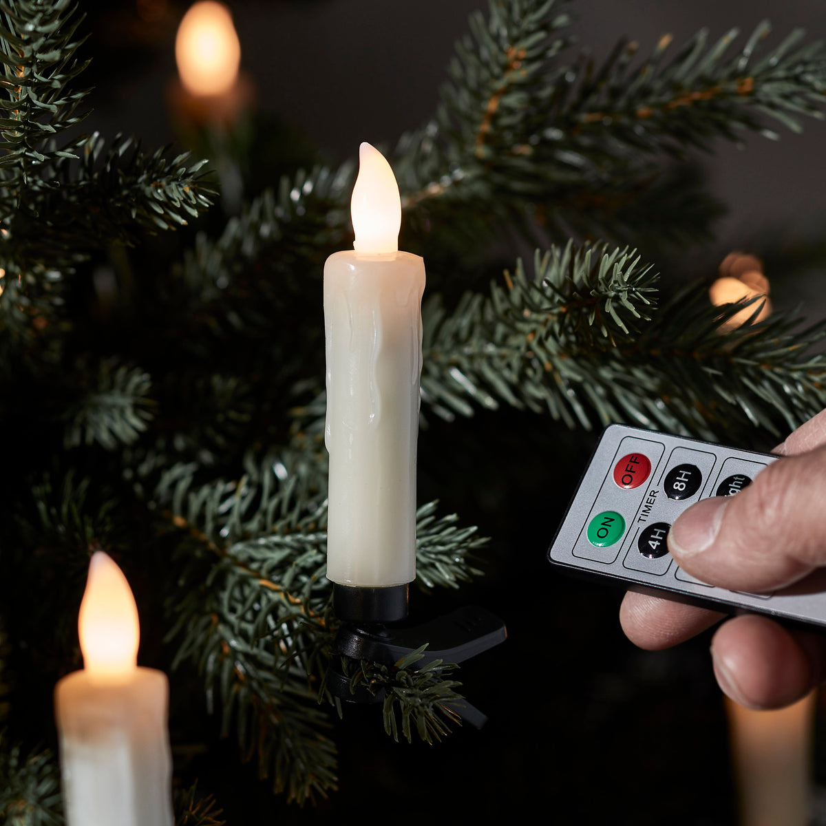 LED-Weihnachtsbaumkerze mit Flammenform und schwarzem Clip an Tannenzweig befestigt