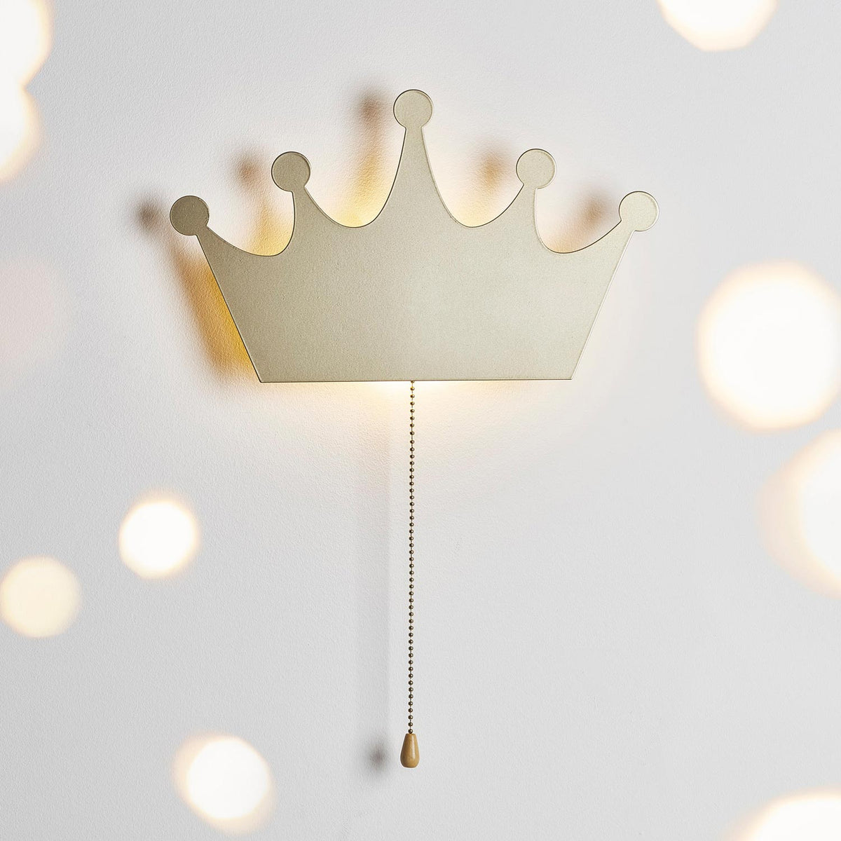 Leuchtende goldene Kronen-Wandlampe mit unscharfen Lichtern im Vordergrund