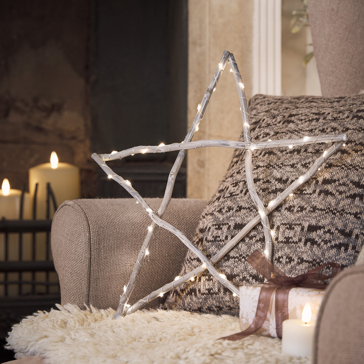 Holzstern mit LED-Lichterkette auf Sofa mit Kissen und Geschenken