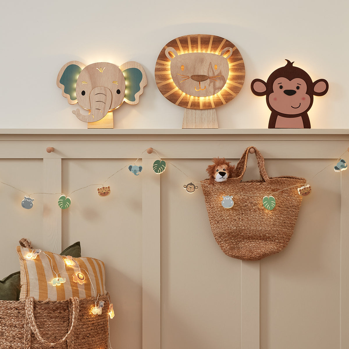 Kinderzimmer mit Safari Lichterkette, Holzfiguren Elefant, Löwe, Affe und Korbtasche an Wand