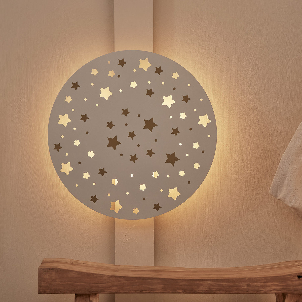 Runde Wandleuchte mit Sternen- und Punktmustern, warmweiß beleuchtet an Wand montiert