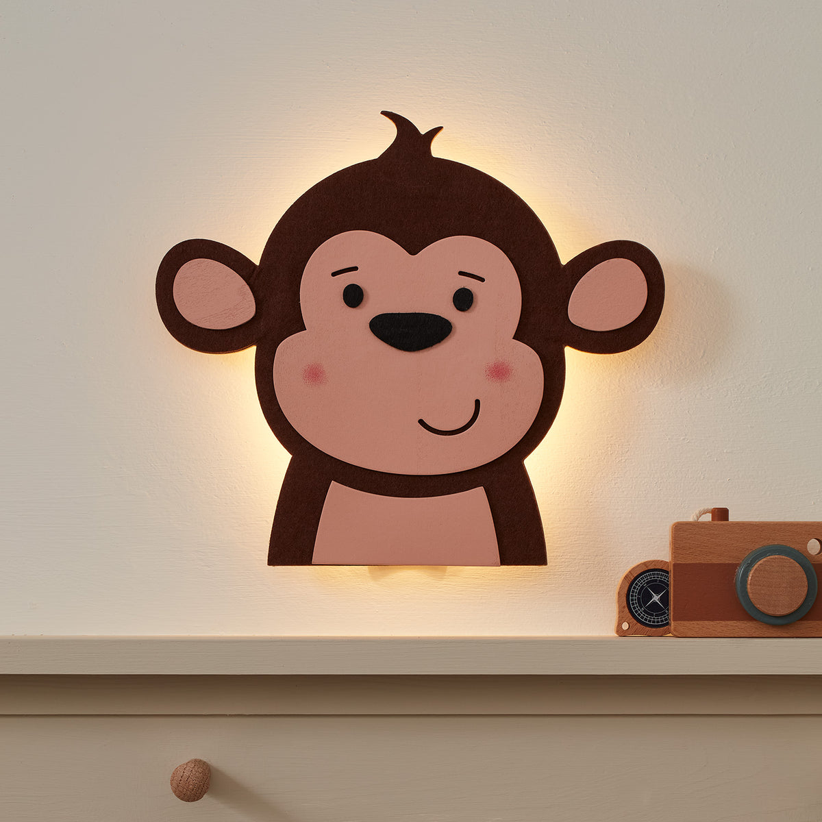 Affen Wandleuchte aus Holz mit warmweißen LEDs leuchtet an Wand über Regal